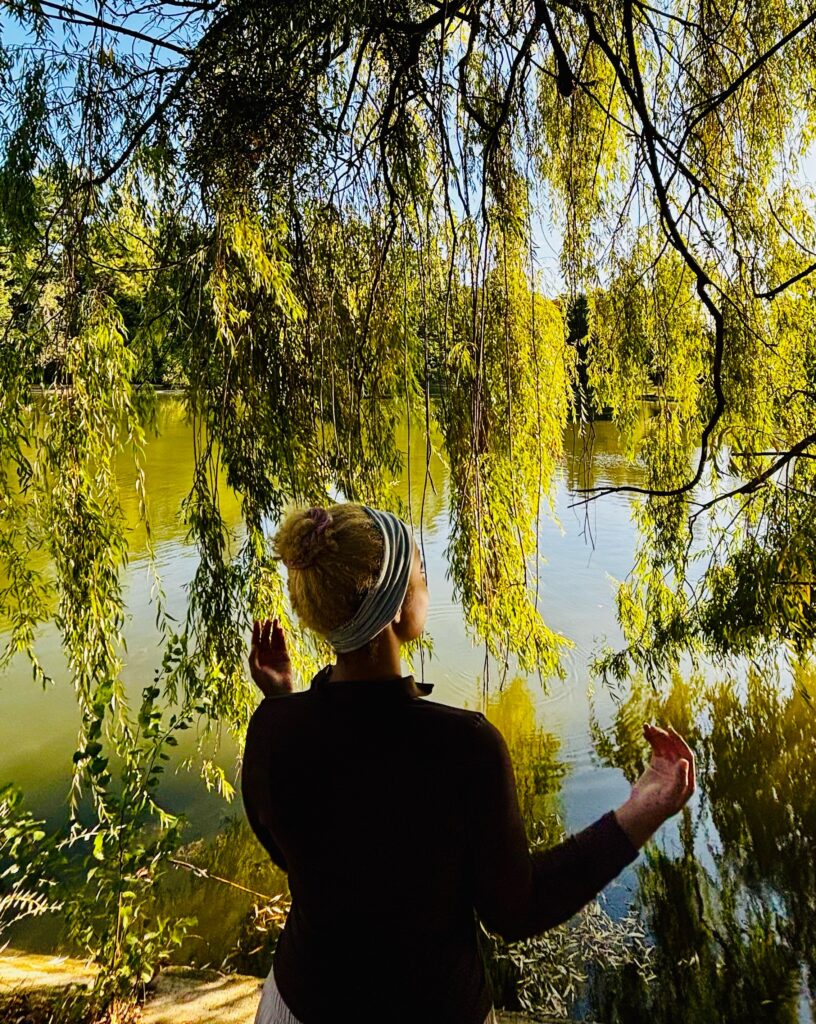 Personne assise face à un plan d’eau, dans une posture calme, illustrant une séance de sophrologie et de recentrage.